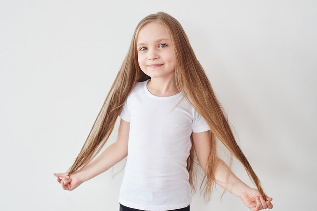 Portrait of little girl holding hair in hands on white background