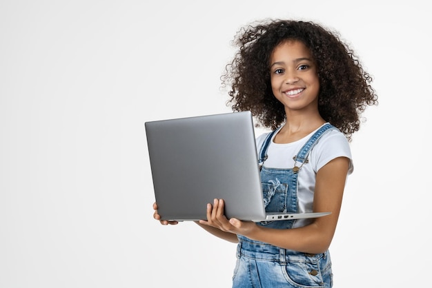 Портрет маленькой девочки, держащей ноутбук, стоя и глядя в камеру
