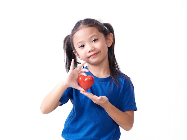 Portrait of little girl holding red heart on white wall. Space for text