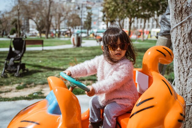 Photo portrait little girl on kiddie ride outdoor having fun