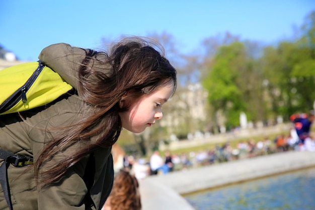Портрет маленькой девочки, смотрящей на воду в парке