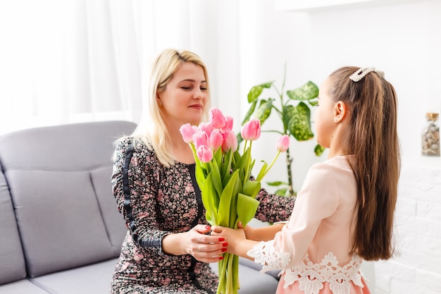 Портрет любящей матери маленькой девочки, держащей ее и тюльпаны
