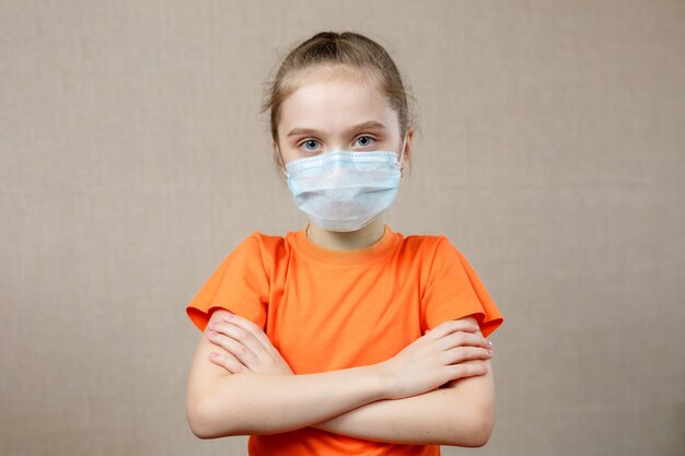 의료 마스크에 작은 소녀의 초상화. 아이 환자는 벽 배경에 서