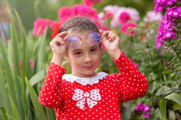 Portrait of little girl in a red dress with polka in glasses