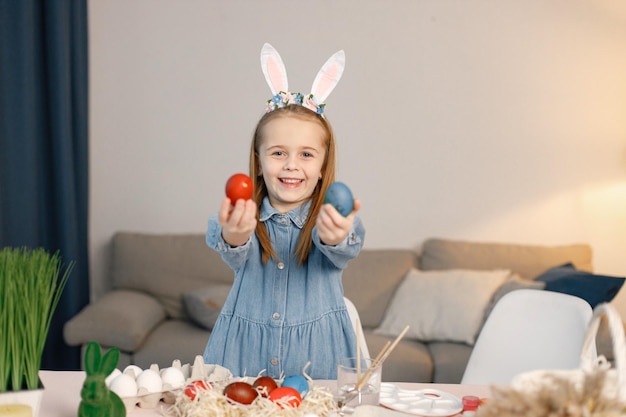 Portrait of little girl standing in modern light kitchen with Easter eggs