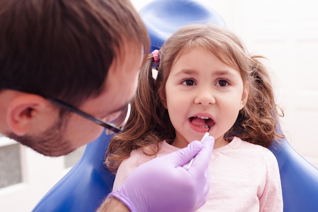 Foto ritratto di una bambina seduta con la bocca aperta e controlla i denti dal dentista