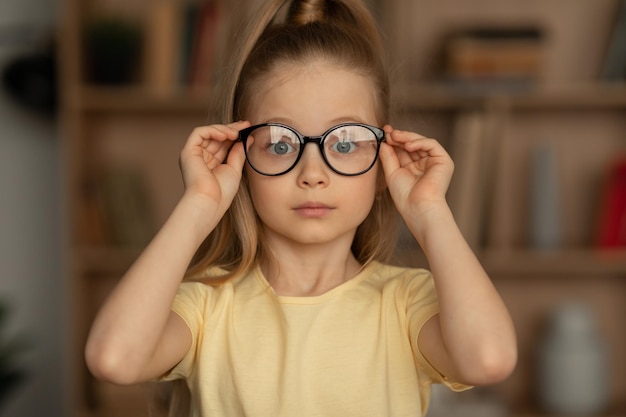 Портрет маленькой девочки в очках, сидящей в библиотеке