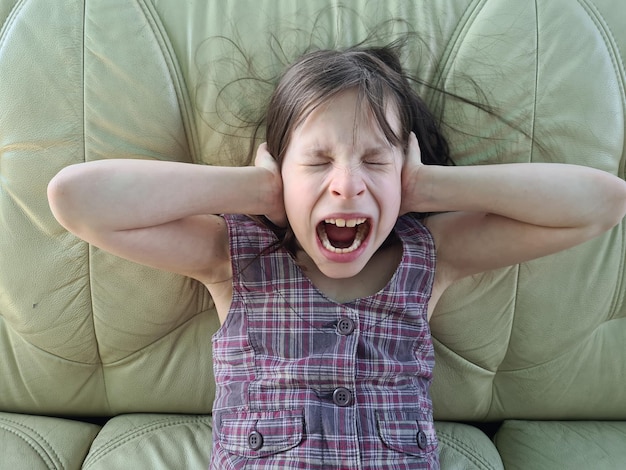 Photo portrait of little girl with blocked ears and screaming