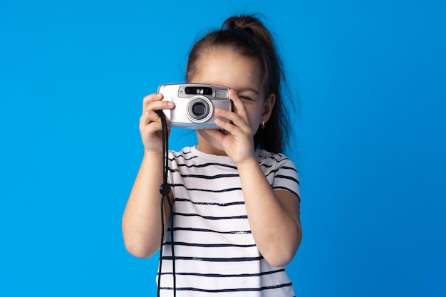 Portrait of a little girl with camera against blue background