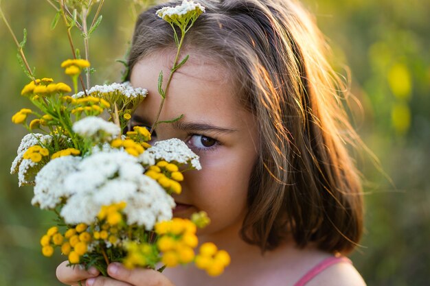 Portrait of a little girl with flowers in the field. 