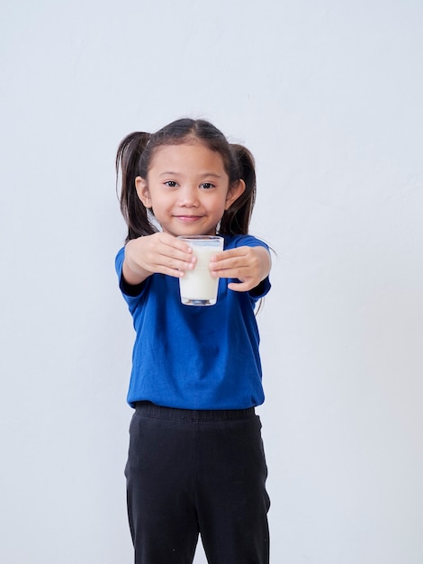 Portrait of little girl with glass of milk on light