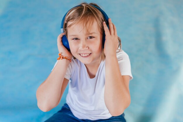 Portrait of a little girl with headphones on a blue background Soft focus