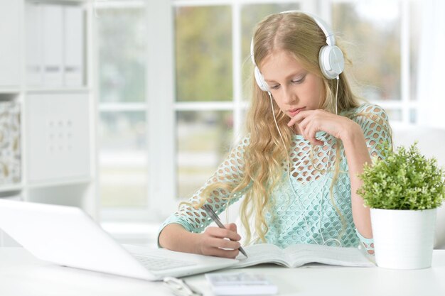 Portrait of a little girl with headphones and laptop