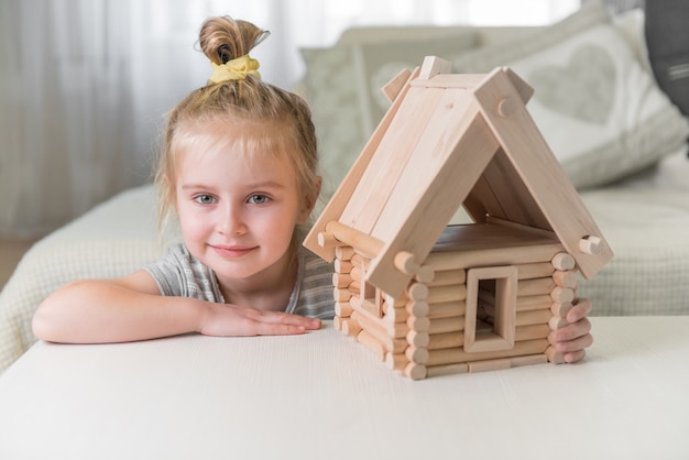 Photo portrait of little girl with house model.