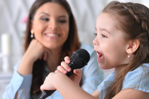 Foto ritratto di bambina con madre che canta al karaoke