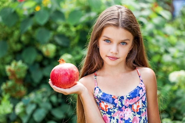 Photo portrait of a little girl with a pomegranate