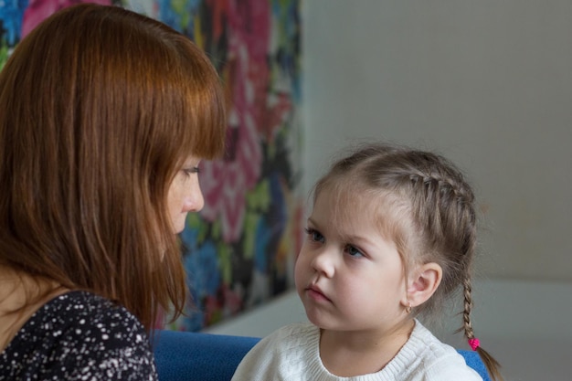 Foto ritratto di bambina con uno sguardo serio guardando sua madre