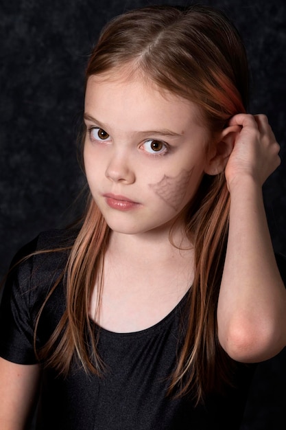 Photo portrait of a little girl with a spider web drawing on her face