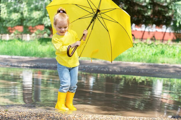 Portrait of a little girl in yellow clothes and with a bright
yellow umbrella in her hands