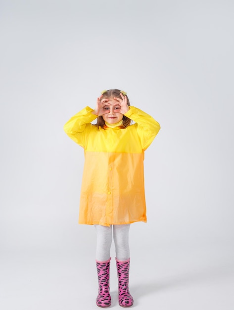 Portrait of a little girl in a yellow raincoat and boots on an isolated white background.