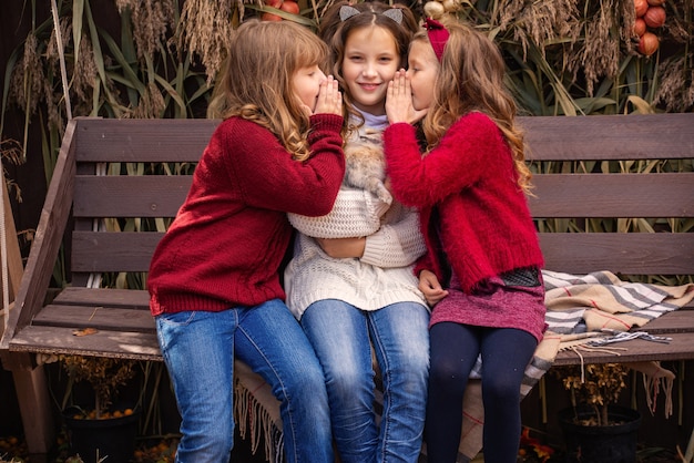 Photo portrait of little girls girlfriends in the fall with a rabbit in their hands near their house fam