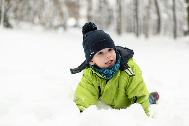 雪の中に横たわる小さな幸せな少年の肖像画