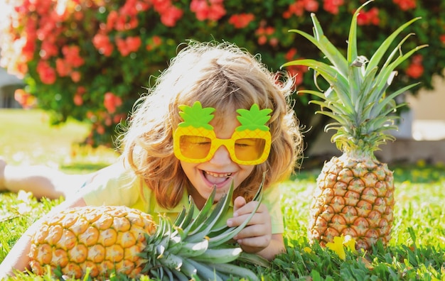 Portrait of little kid outdoors in summer Smiling cute funny boy holding a pineapple
