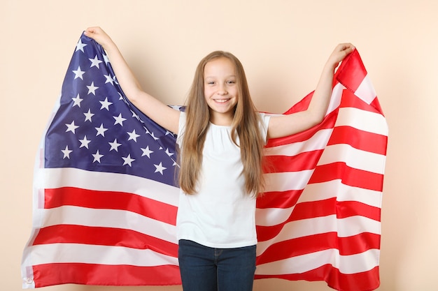 Portrait of a little positive girl with an american flag in her hands