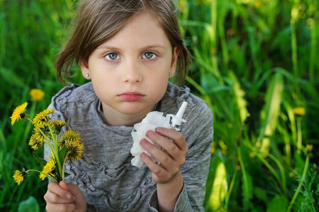 Portrait of little sad girl with allergy symptoms in nature