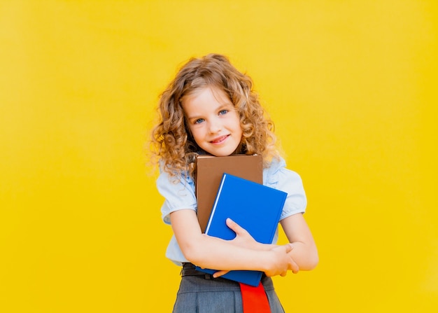 彼女の頭の上に本を持っている小さな女子高生の肖像画。孤立した背景。教育の概念。