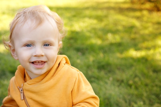 Portrait of a little smiling baby on a walk in the park place for text banner