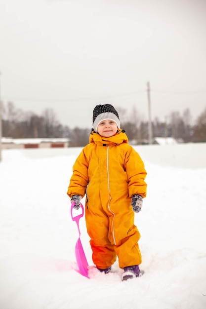 Портрет маленькой трехлетней девочки в зимнем комбинезоне на прогулке зимой