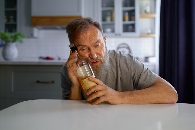 Portrait of lonely drunk man feeling depressed on home kitchen