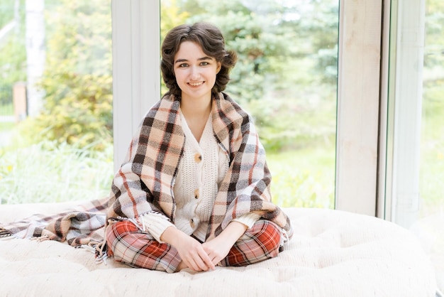 Portrait lonely saucasian young woman sitting near window apartments in a whit