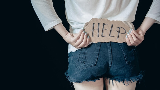 Portrait of lonely teenage person despair girl standing alone with sad expression and showing a paper with a help text concept of problem domestic violence against women