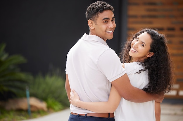 Portrait love and couple happy in front of new home or house hug as they stand on driveway with a smile Real estate investment in future and property with man and woman spending time together