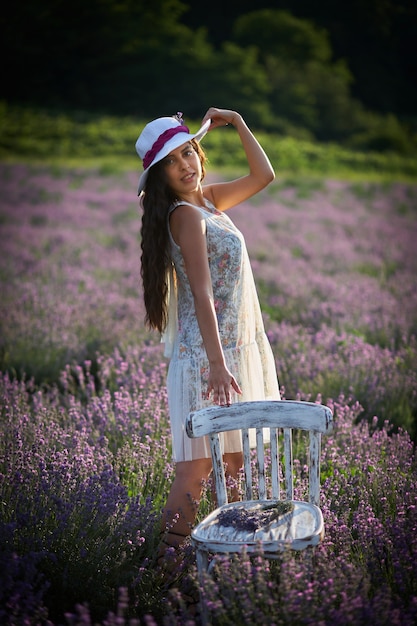 Ritratto di bella ragazza bruna con cappello su sfondo di campo di lavanda.