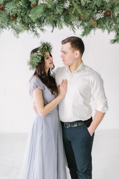 Portrait of lovely couple on white wall and pine decoration