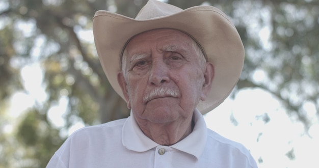 Portrait of lovely elderly man in the summer park looking to the camera, hope and trust.