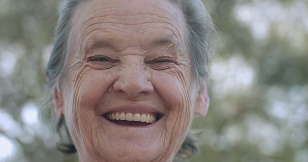 Ritratto di bella donna anziana nel parco estivo sorridente.