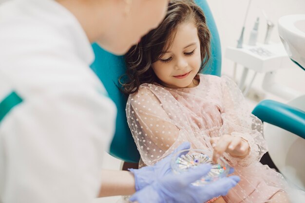 Ritratto di una bella bambina che mostra con il dito con quello che dovrebbe lavorare lo stomatologo pediatrico.