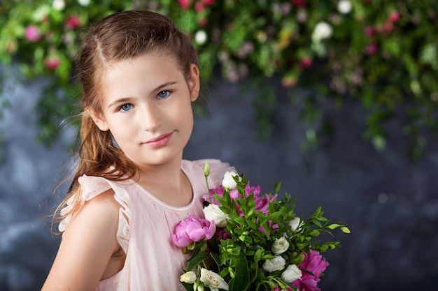 Ritratto della bella bambina con un mazzo di fiori.