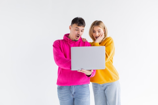 Portrait of lovely man and woman holding silver laptop while standing isolated over white background