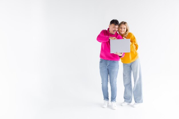 Photo portrait of lovely man and woman holding silver laptop while standing isolated over white background