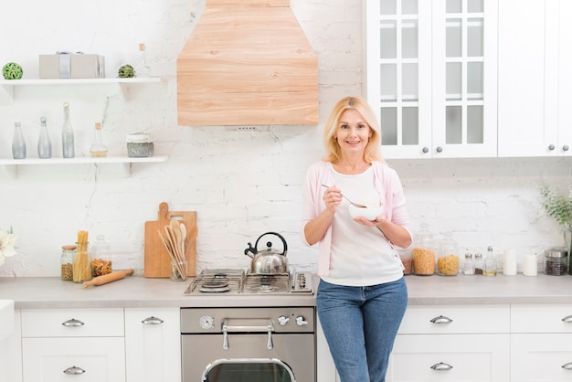 Foto ritratto della donna senior adorabile che mangia prima colazione