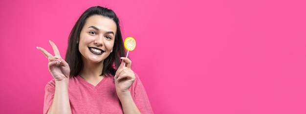 Portrait of lovely sweet beautiful cheerful woman with straight brown hair holding a lollipop near the eyes