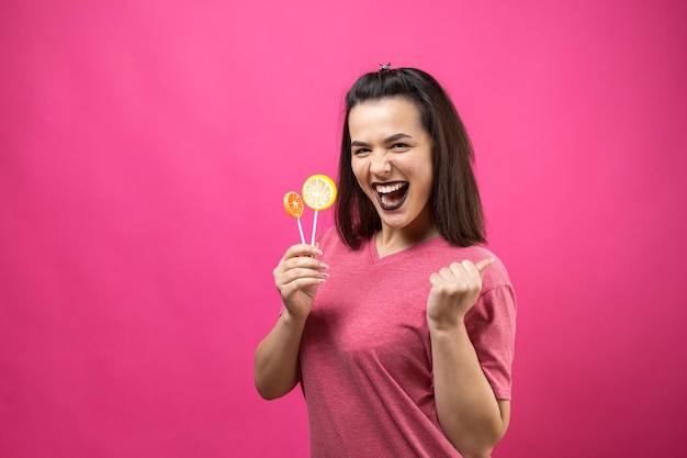 Portrait of lovely sweet beautiful cheerful woman with straight brown hair holding a lollipop