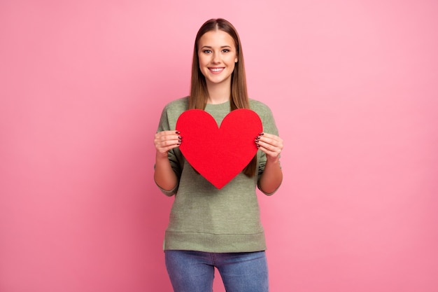 Il ritratto della ragazza dolce adorabile tiene il grande cuore rosso della carta di carta