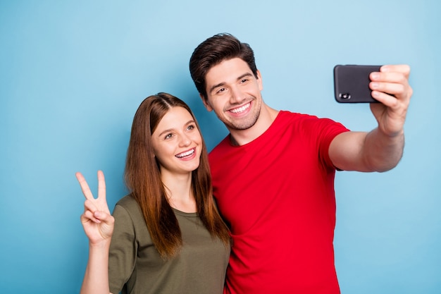 Portrait of lovely two married people bloggers rest relax on resort make selfie feel romance romantic wear red green t-shirt isolated over blue color background