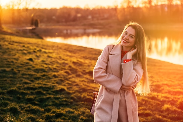 Portrait of a lovely young girl in front of a lake and sunset. Warm Sunset Colors.